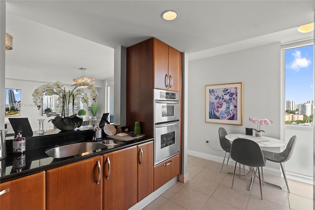 kitchen featuring decorative light fixtures, stainless steel double oven, sink, and light tile patterned floors