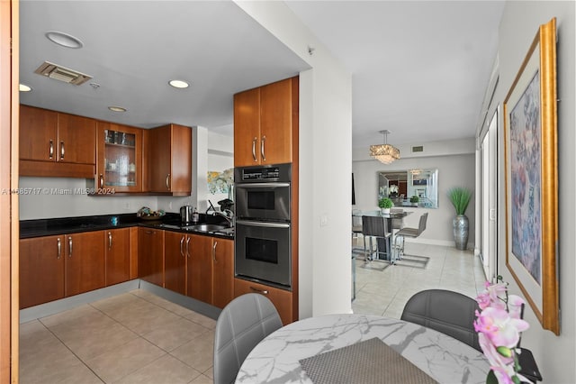 kitchen featuring light tile patterned flooring, stainless steel double oven, decorative light fixtures, and sink