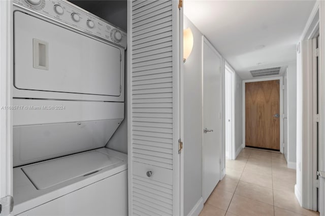 laundry room featuring stacked washer and dryer and light tile patterned floors