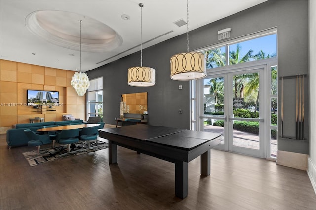 rec room with a raised ceiling, french doors, a towering ceiling, and wood-type flooring