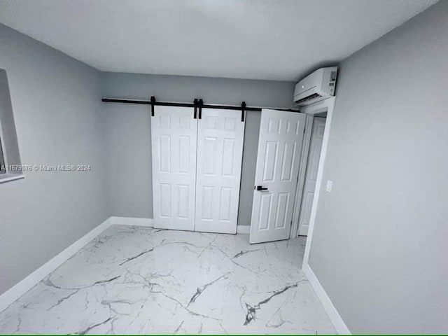 unfurnished bedroom featuring a closet, a barn door, and a wall mounted AC