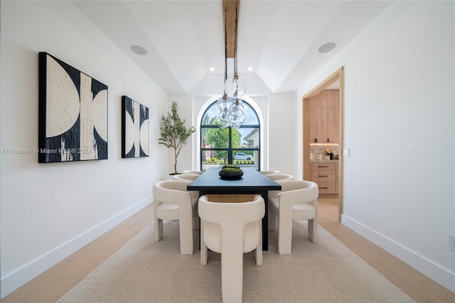 dining room with vaulted ceiling with beams and light wood-type flooring