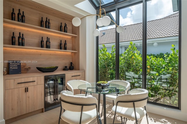 bar featuring light brown cabinets, beverage cooler, and plenty of natural light