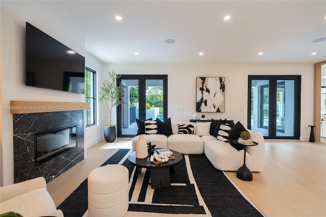 living room featuring french doors, a fireplace, and light hardwood / wood-style floors