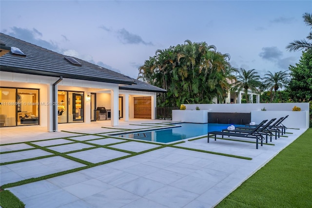 pool at dusk with a patio area