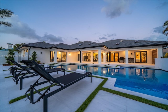 pool at dusk with a patio area