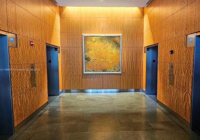 hall with tile walls, a high ceiling, and elevator