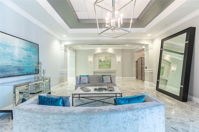 living room with crown molding, a notable chandelier, a raised ceiling, and decorative columns