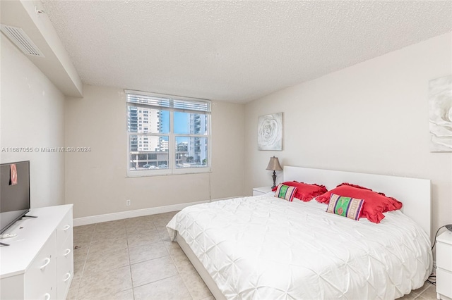 bedroom with a textured ceiling and light tile patterned flooring