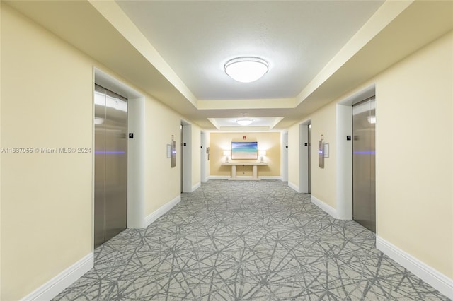 corridor with a tray ceiling and elevator