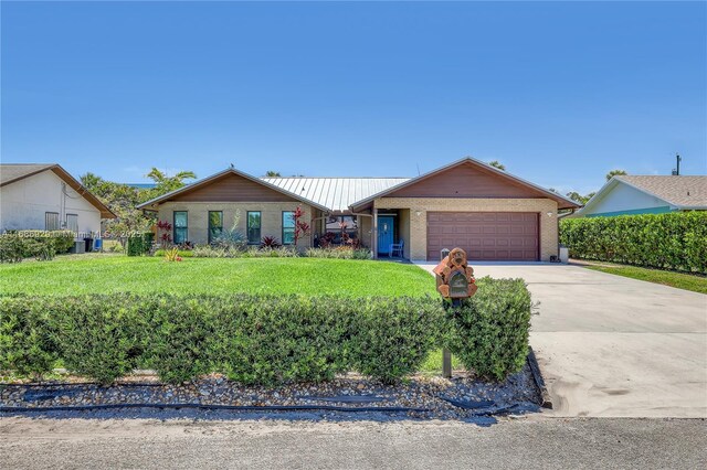 4706 SE Manatee Ter, Stuart, FL 34997 - ranch-style home featuring an attached garage, driveway, brick siding, and a front lawn