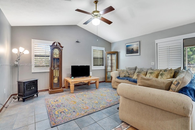 tiled living room featuring ceiling fan, plenty of natural light, a wood stove, and lofted ceiling