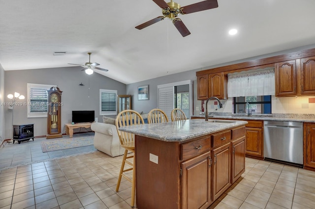 kitchen with light tile patterned floors, a wood stove, a kitchen island with sink, a kitchen breakfast bar, and dishwasher