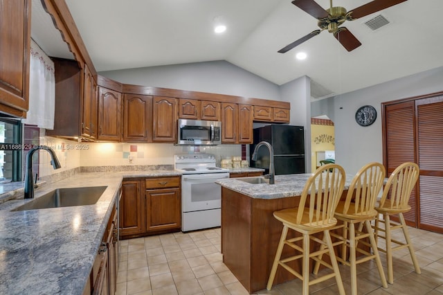 kitchen with an island with sink, electric stove, backsplash, sink, and a breakfast bar