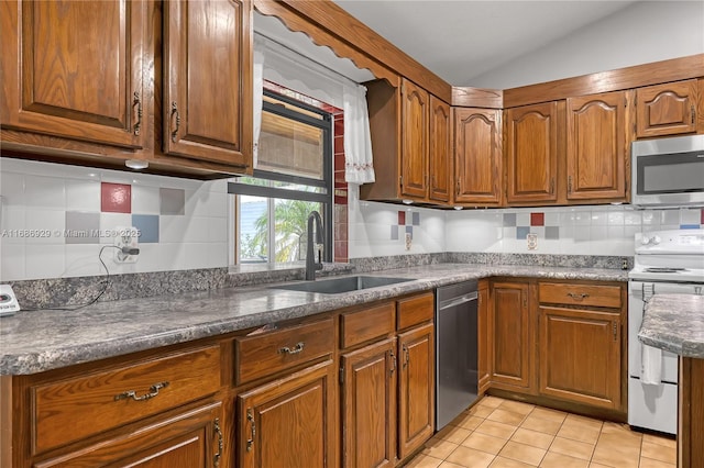 4706 SE Manatee Ter, Stuart, FL 34997 - kitchen featuring stainless steel appliances, a sink, brown cabinets, tasteful backsplash, and vaulted ceiling