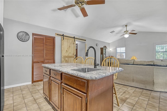4706 SE Manatee Ter, Stuart, FL 34997 - kitchen featuring a sink, a ceiling fan, vaulted ceiling, a breakfast bar area, and a barn door