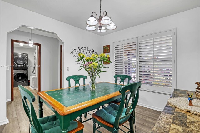 4706 SE Manatee Ter, Stuart, FL 34997 - dining area featuring stacked washer / drying machine, a chandelier, arched walkways, wood finished floors, and baseboards
