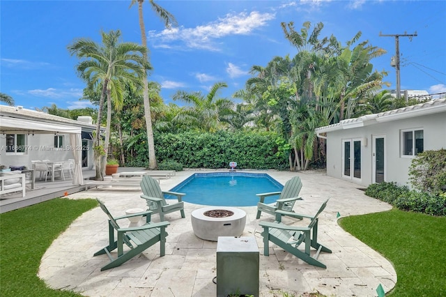 outdoor pool with a fire pit, french doors, and a patio area