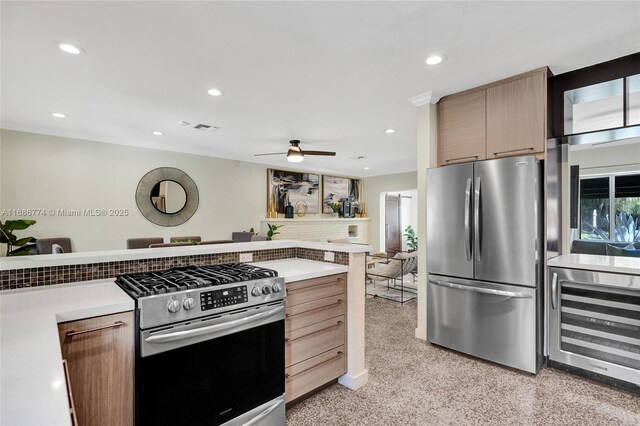 kitchen with appliances with stainless steel finishes, light brown cabinets, beverage cooler, and ceiling fan