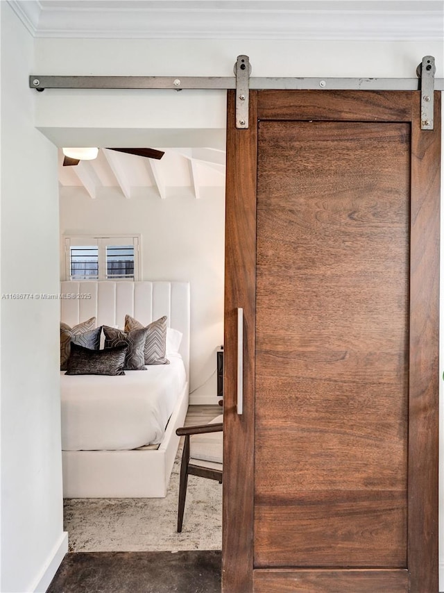 bedroom with a barn door and beamed ceiling