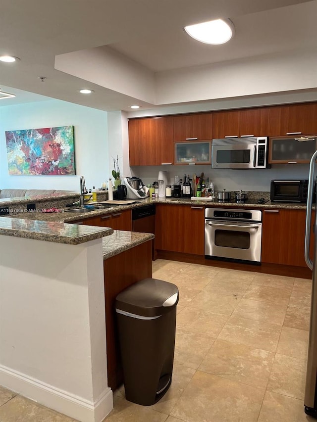 kitchen with dark stone countertops, stainless steel appliances, sink, and kitchen peninsula