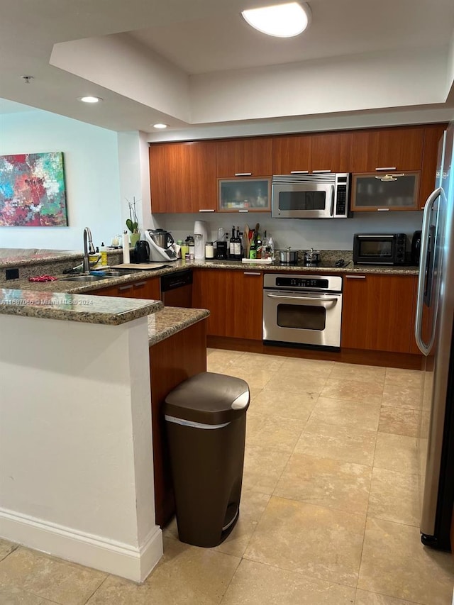 kitchen with stone counters, stainless steel appliances, sink, and kitchen peninsula