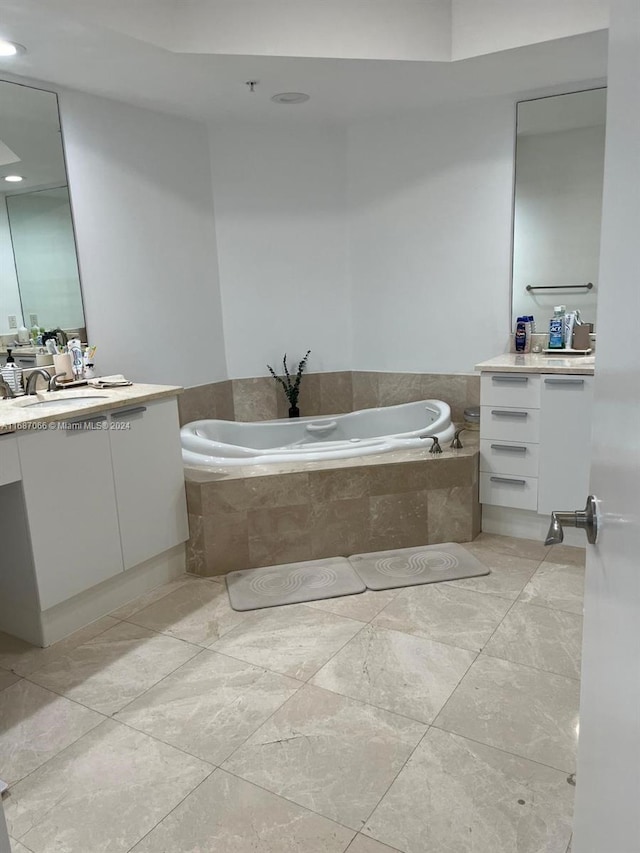 bathroom featuring vanity, a relaxing tiled tub, and tile patterned flooring