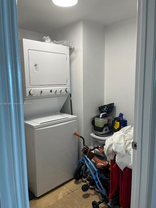 clothes washing area with light tile patterned flooring and stacked washer and dryer