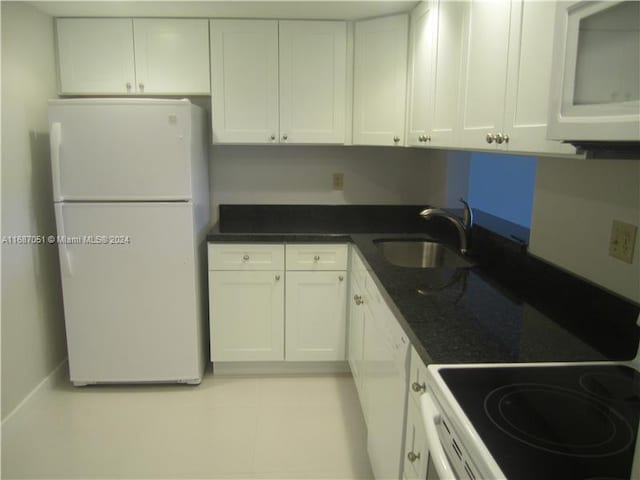 kitchen with white appliances, sink, dark stone counters, and white cabinets