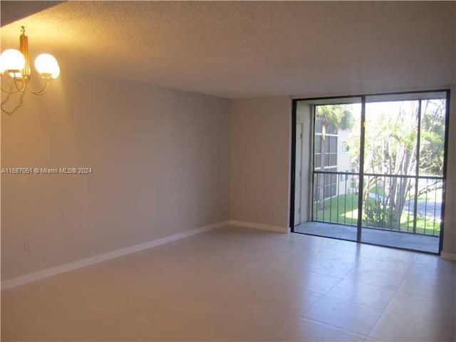 empty room featuring a notable chandelier and a textured ceiling