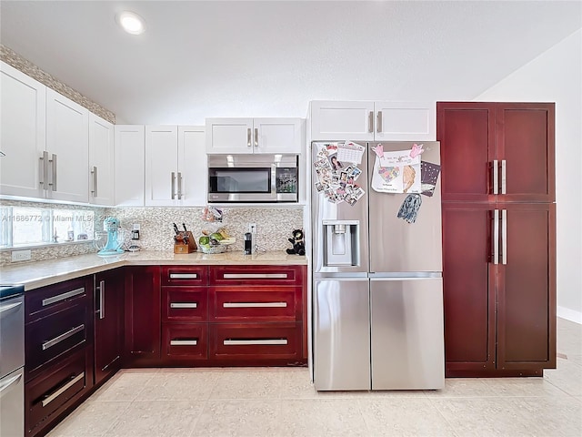 kitchen with decorative backsplash, appliances with stainless steel finishes, white cabinets, and light tile patterned flooring