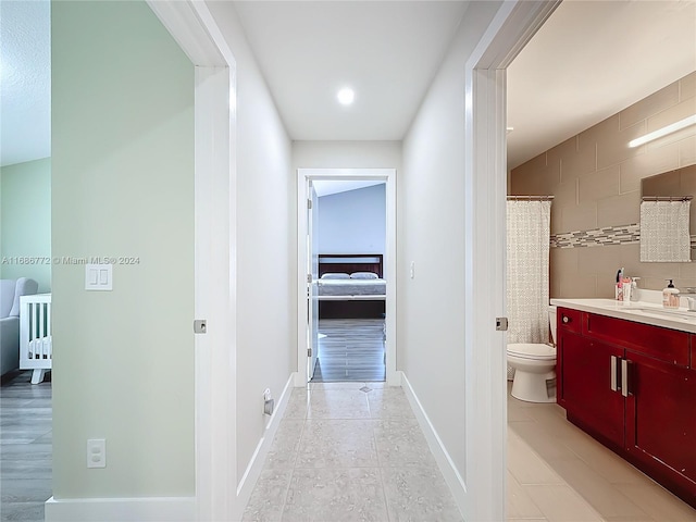 corridor with sink, tile walls, and light wood-type flooring