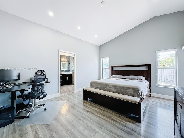 bedroom featuring light hardwood / wood-style flooring, connected bathroom, and vaulted ceiling