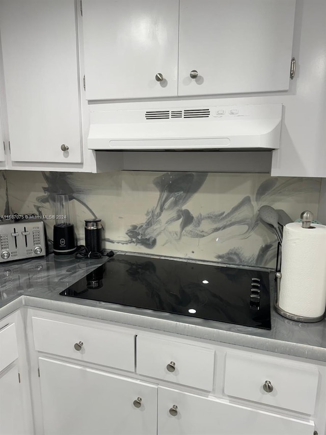 kitchen with exhaust hood, white cabinets, black electric stovetop, tasteful backsplash, and light countertops