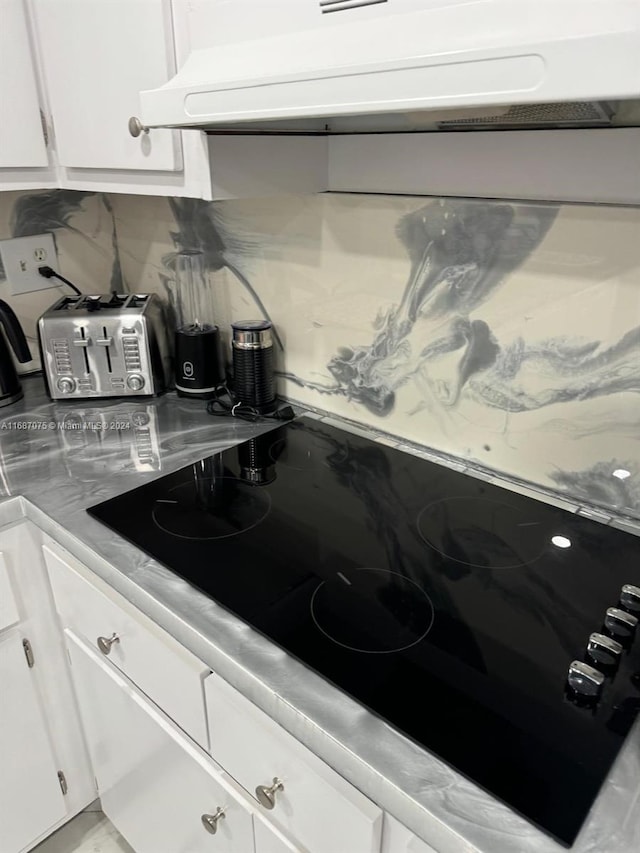 kitchen with exhaust hood, white cabinetry, decorative backsplash, and black electric stovetop