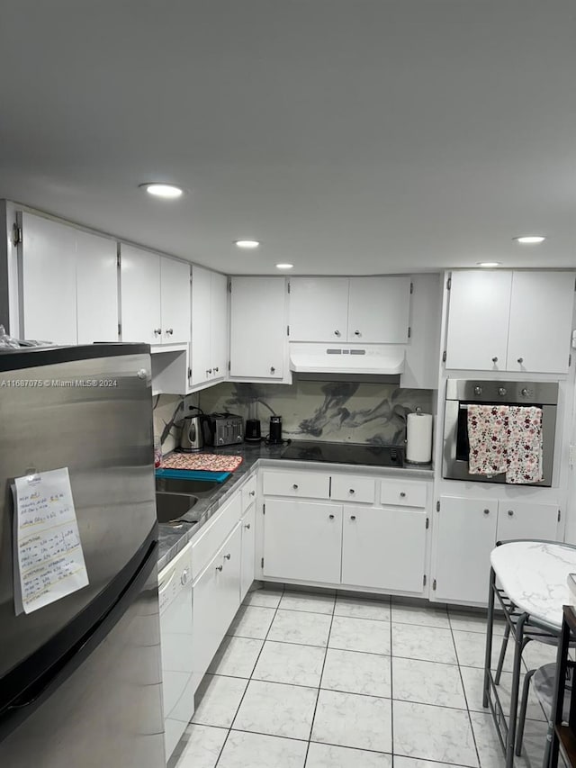 kitchen with appliances with stainless steel finishes, under cabinet range hood, dark countertops, white cabinetry, and light tile patterned floors
