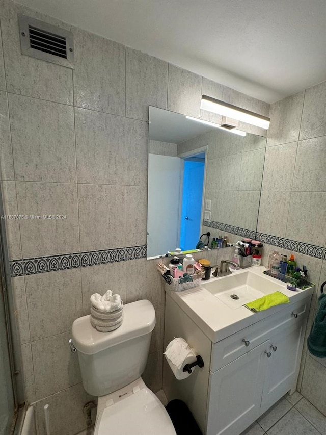 bathroom featuring vanity, toilet, tile walls, and tile patterned flooring