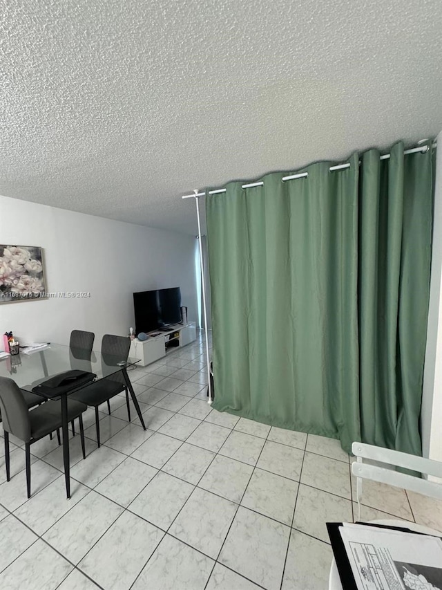 dining space with a textured ceiling and light tile patterned floors