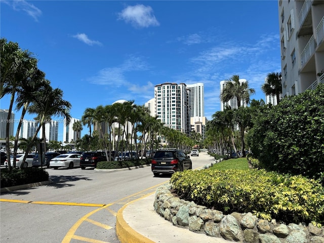 view of asphalt road featuring curbs, a city view, and sidewalks