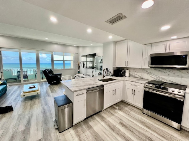 kitchen featuring white cabinetry, stainless steel appliances, sink, and a water view