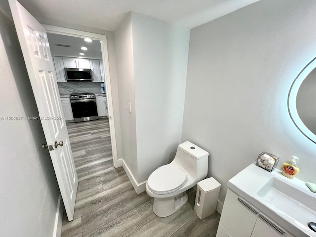 bathroom with backsplash, vanity, wood-type flooring, and toilet