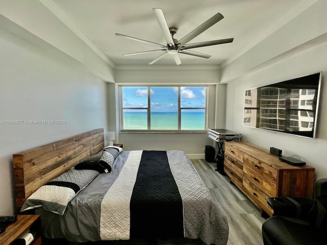 bedroom with ornamental molding, light wood-type flooring, a water view, and ceiling fan