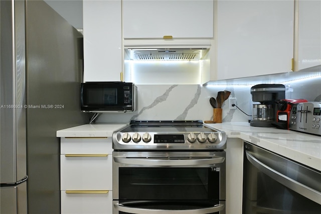 kitchen featuring backsplash, electric range, light stone counters, and white cabinetry