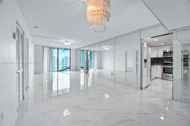 unfurnished room featuring a textured ceiling and a chandelier