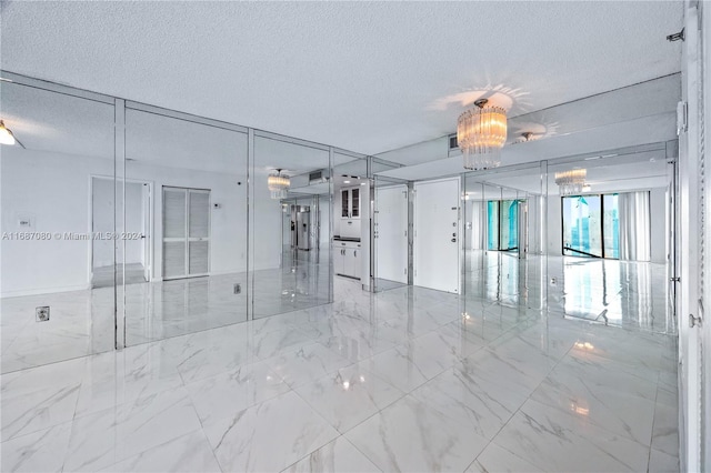 empty room with a textured ceiling and an inviting chandelier