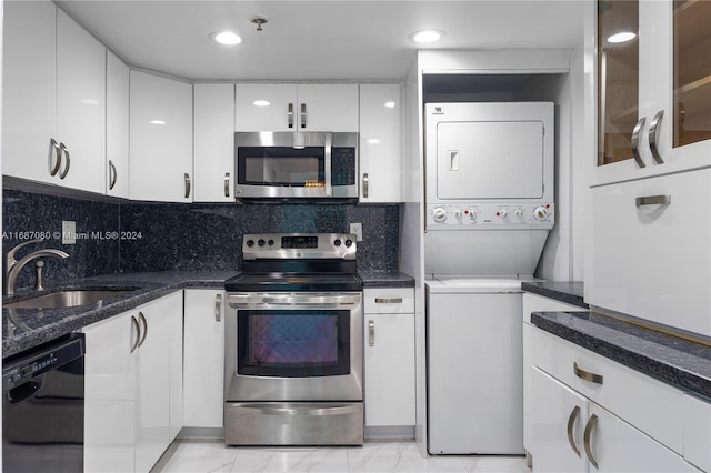 kitchen featuring sink, stacked washer / dryer, backsplash, stainless steel appliances, and white cabinets