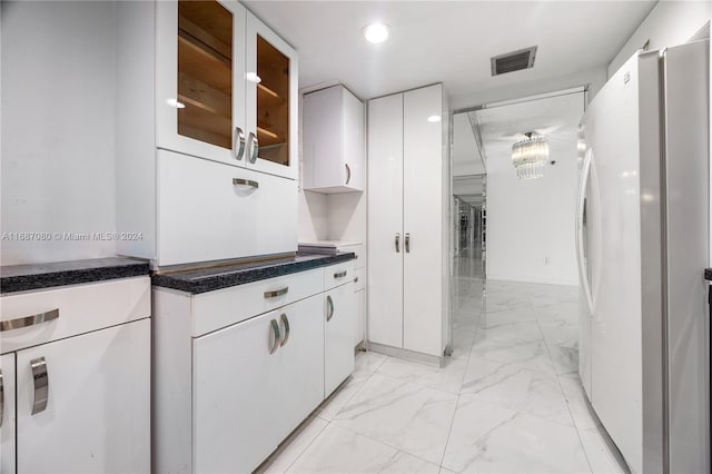 210 174th St Unit 1906, Sunny Isles Beach, FL 33160 - kitchen with freestanding refrigerator, light marble finish flooring, white cabinets, baseboards, and glass insert cabinets