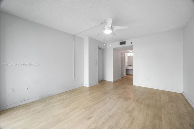 empty room featuring a textured ceiling, light wood-type flooring, and ceiling fan