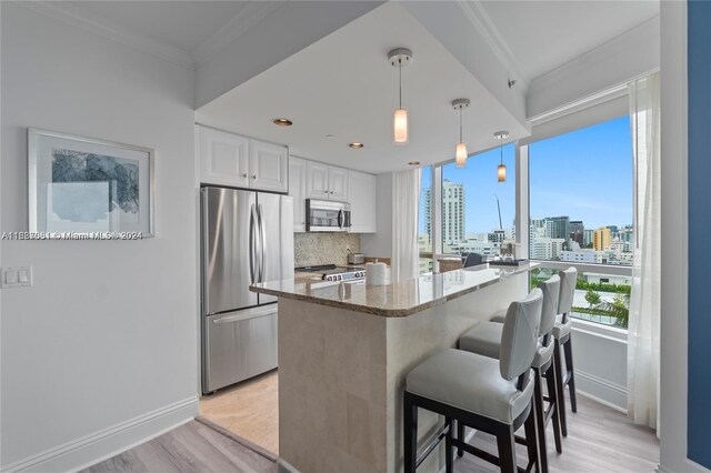 4401 Collins Ave Unit 1214, Miami Beach, FL 33140 - kitchen featuring appliances with stainless steel finishes, a kitchen bar, light wood-style floors, stone counters, and white cabinetry