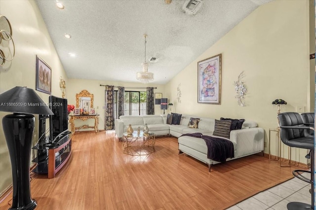 living room with a textured ceiling, lofted ceiling, and light wood-type flooring